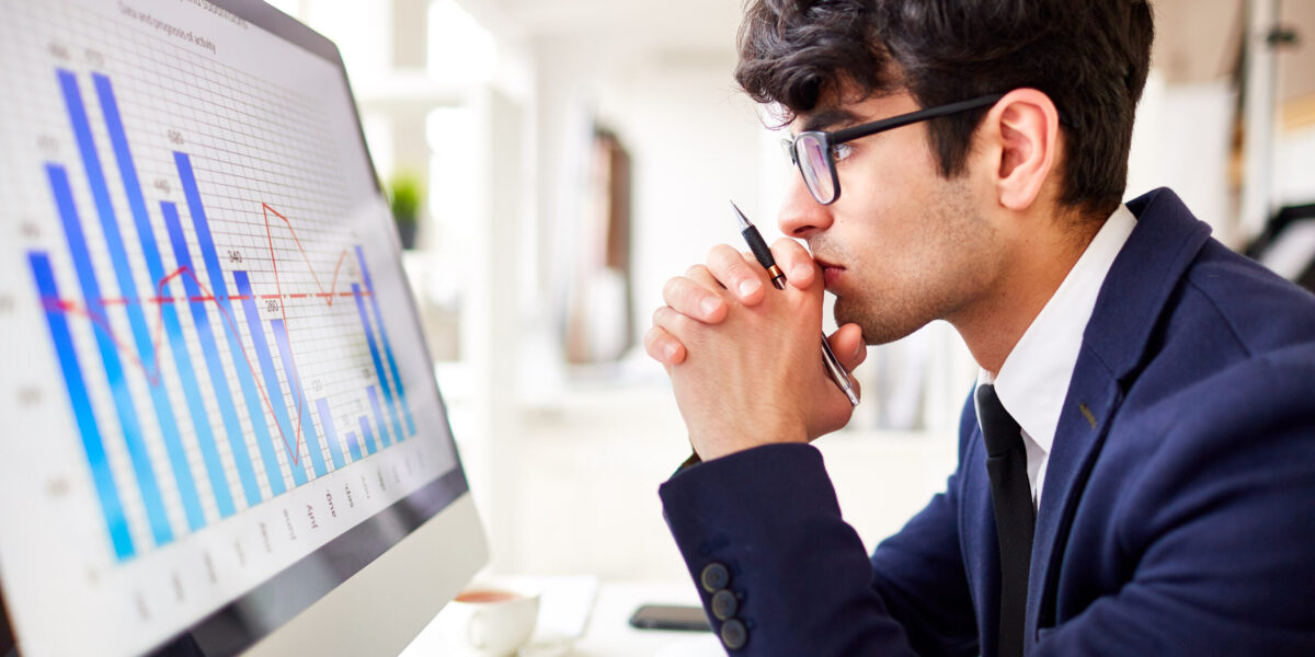 Side view of pensive man looking at financial chart in computer monitor