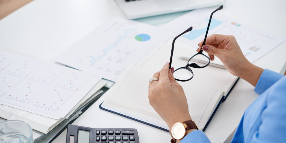 Hands of business woman putting on her glasses before working with documents