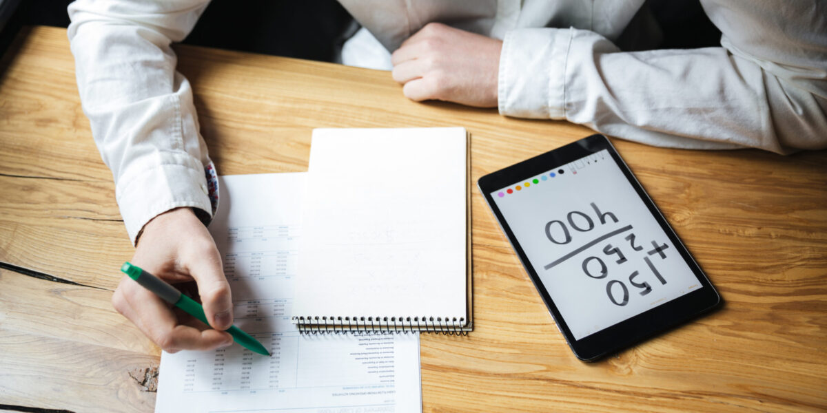 Cropped photo of businessman in white shirt working on wooden table