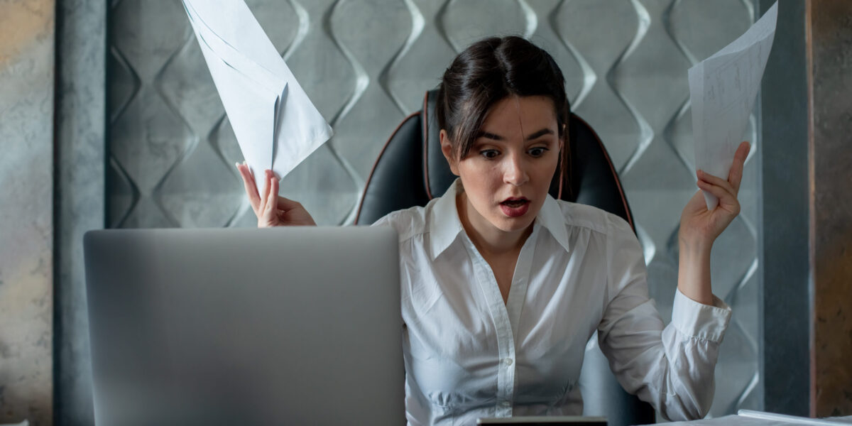 portrait of young office worker woman sitting at office desk with documents looking at them disappointed nervous and stressed working in office